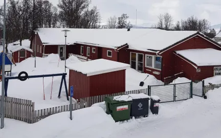 Amaliahaugen barnehage sett utenfra Amaliahaugen barnehage og uteområde med husker og leketårn en snørik vinterdag