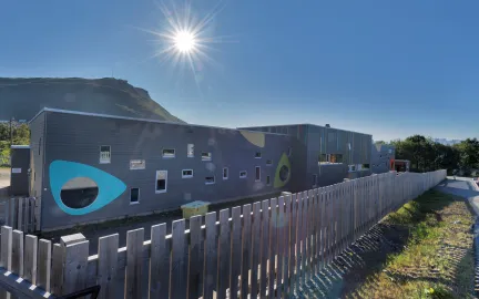Elvestrand barnehage sett utenfra en solrik sommerdag med bl&aring; himmel