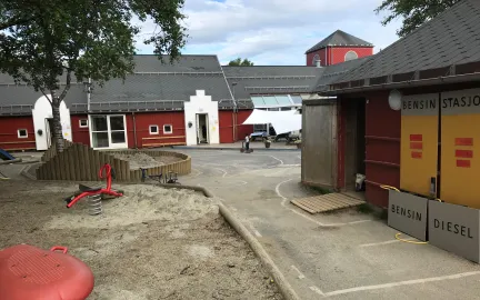 Olsgård barnehage uteområde Olsgård barnehage uteområde med et stort tre, sandkasser og lekeapparater en sommerdag