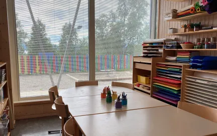 Inneomr&aring;de i Sj&oslash;mannsbyen barnehage med formingsrom, sitteomr&aring;de med fargestifter og hyller med farget papir.