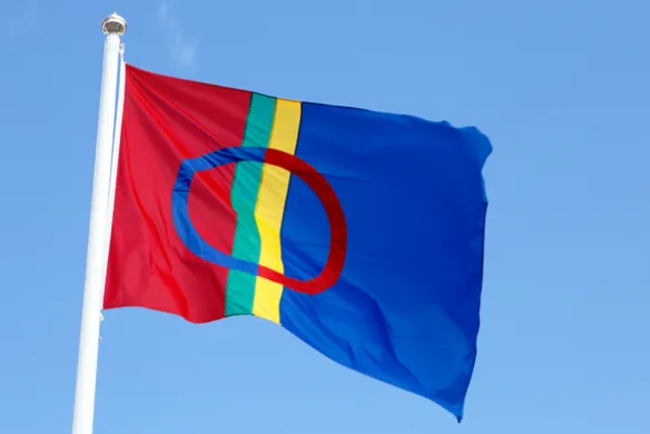 Det samiske flagget Det samiske flagget på flaggstang mot blå himmel. Foto.