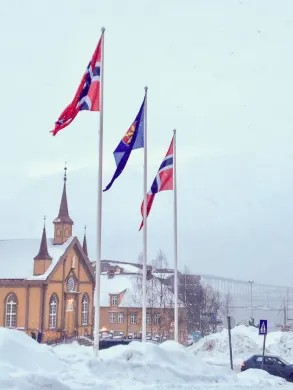 To norske og et kvensk flagg vaier utenfor Troms&oslash; r&aring;dhus i mars 2019