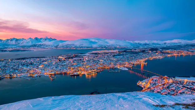 Panoramabilde av et sn&oslash;kledt Troms&oslash;ya tatt fra fjellheisen i Tromsdalen.