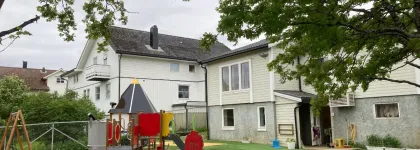Bamsestua friluftsbarnehage uteomr&aring;de med lekeapparater en gr&aring; sommerdag