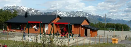 Uteomr&aring;de p&aring; Skittenelv barnehage med sandkasser og husker, bl&aring; himmel en solrik sommerdag