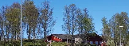 Ameliahaugen barnehage sett utenfra en fin sommerdag med tr&aelig;r og bl&aring; himmel