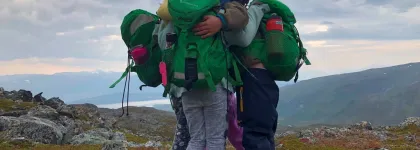 Tre barn holder rundt hverandre p&aring; en fjelltopp en tidlig h&oslash;stdag