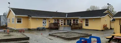Uteomr&aring;de med sandkasse, benker og bord i Polarhagen barnehage