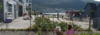 To jenter holder hender og leker i uteomr&aring;det i Strandkanten FUS barnehage