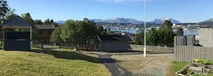 Uteomr&aring;de Kroken barnehage med utsikt mot Troms&oslash;ya en solrik sommerdag