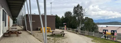 Uteomr&aring;de med benker og klatret&aring;rn en sen sommerdag med skyer og bl&aring; himmel.